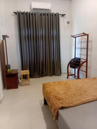 a room with a bed and a chair and a window at Mivin Villa - Madiha in Godakanda