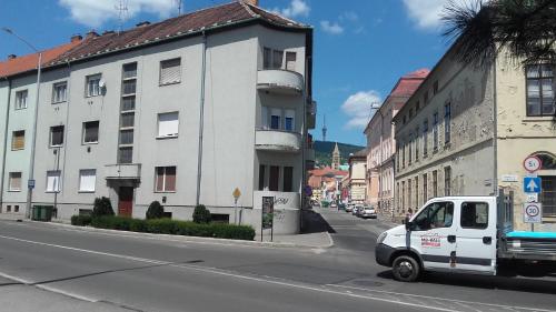 a white van driving down a city street with buildings at Anna Apartmanok in Pécs