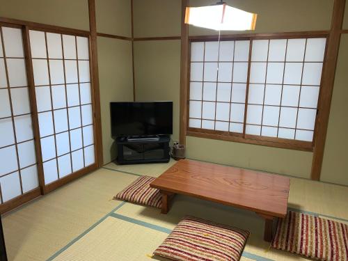 a living room with a table and a tv at Cottage Karuizawa in Karuizawa