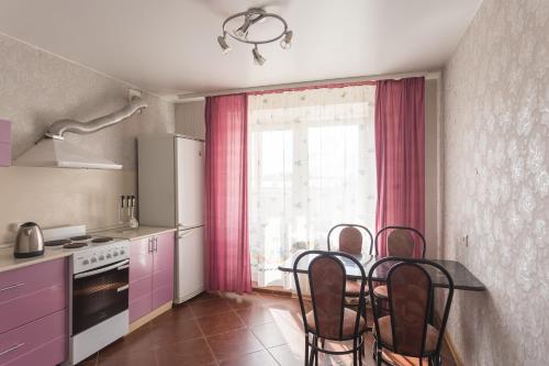 una cocina con armarios rosados y una mesa con sillas. en Хочу Приехать на улице Чехова, en Vólogda
