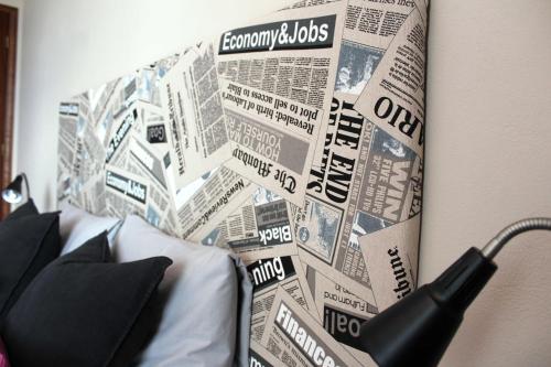 a bed with a wall covered in newspapers at Hello Terceira in Angra do Heroísmo