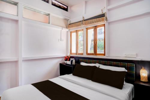 a bedroom with a bed with white walls and windows at Super Collection O Police Bazar Shillong Formerly Pillars House in Shillong