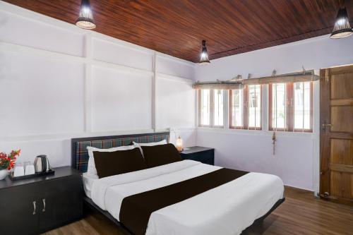 a bedroom with a white and black bed and windows at Super Collection O Police Bazar Shillong Formerly Pillars House in Shillong