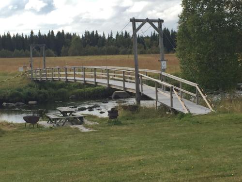 a bridge over a river with a picnic table at Villa Insikt Pensionat & Kursgård in Burträsk