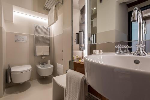 a bathroom with a sink, toilet and bathtub at Hotel Rialto in Venice