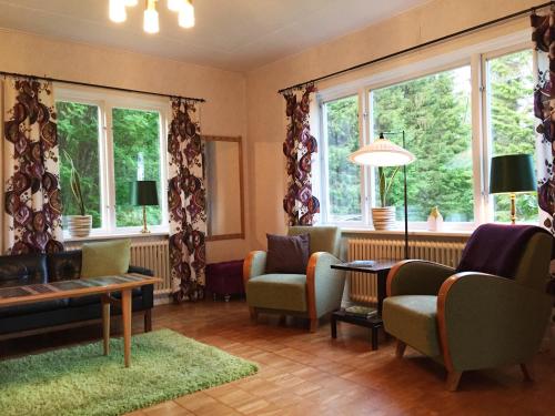 uma sala de estar com cadeiras, uma mesa e janelas em Villa Insikt Pensionat & Kursgård em Burträsk