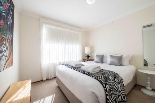 a white bedroom with a large bed and a window at Daisy's Lodge - Relaxed & Family-Friendly Stay in Dubbo