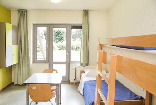 a bedroom with two bunk beds and a table and a desk at Hostel Europa in Bruges