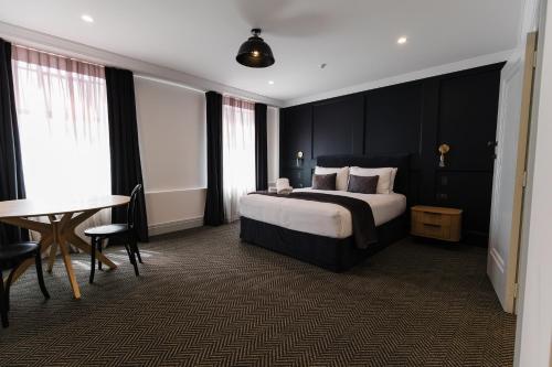 a bedroom with a bed and a table and a desk at Criterion Hotel Napier in Napier