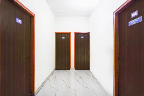 um corredor com duas portas castanhas num edifício em Hotel O A G M Residency em Sohna