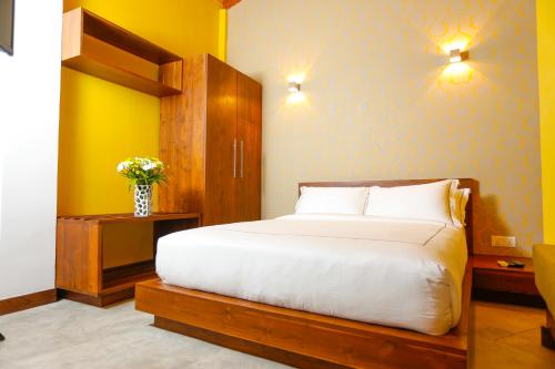 a bedroom with a large white bed and a yellow wall at Viyana Boutique Hotel in Kandy