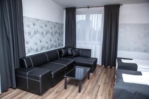a living room with a black couch and a table at Hotel Bukowiec in Legionowo