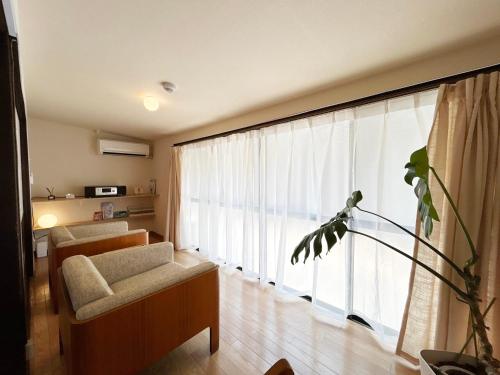 a living room with a couch and a large window at MINI HOTEL totonoi ロウリュ式サウナのある静かな平屋 in Shimonoseki
