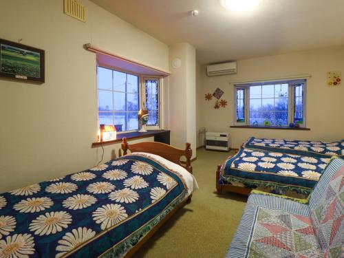 een slaapkamer met twee bedden en twee ramen bij Natsumi no Sato in Biei