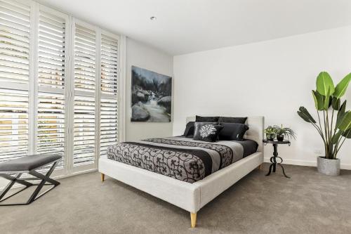 a white bedroom with a bed and a chair at Ivanhoe Five Luxury Holiday Home 4 Bed Sleep 6 in Melbourne