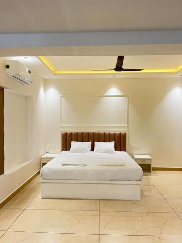 a bedroom with a white bed with a ceiling at Aagneyam Grand Resort in Kozhikode