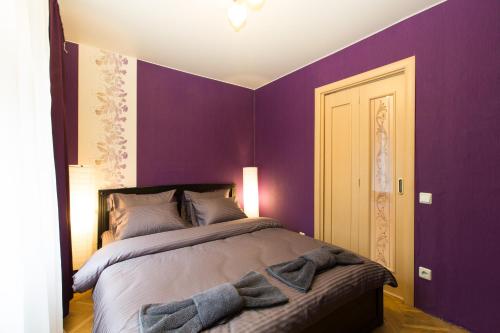 モスクワにあるLux Apartments Taganskayaの紫の壁のベッドルーム1室、ベッド1台(タオル付)