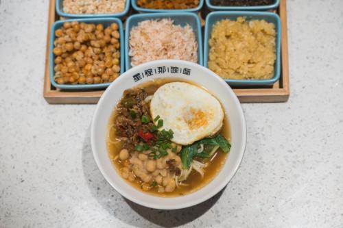 een kom soep met een ei erop en een dienblad met eten bij Starway Hotel Chongqing Nanbin Road Riverview in Chongqing