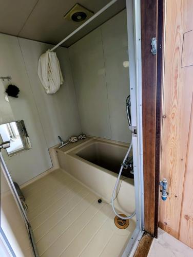 a bathtub in a small room with a hose at Migiwa House in Rankoshi