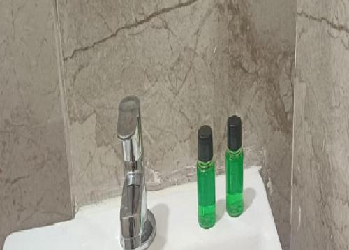 two green bottles sitting on top of a sink at Hotel Soni Indore in Indore