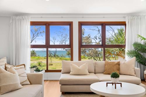a living room with a white couch and windows at Absolute Beachfront Paradise in Buddina in Buddina