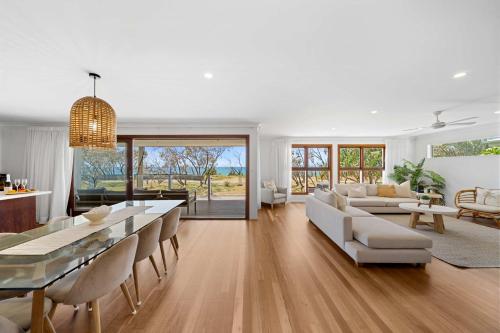a living room with white furniture and a table at Absolute Beachfront Paradise in Buddina in Buddina