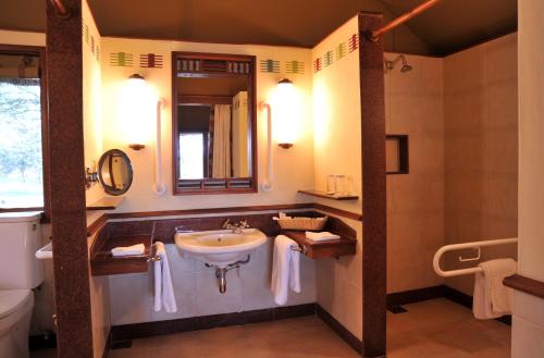 a bathroom with a sink and a toilet and a mirror at Sweetwaters Serena Camp in Nanyuki