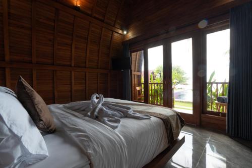 a bedroom with a bed with white sheets and a window at Arta Bali Glamping in Tianyar