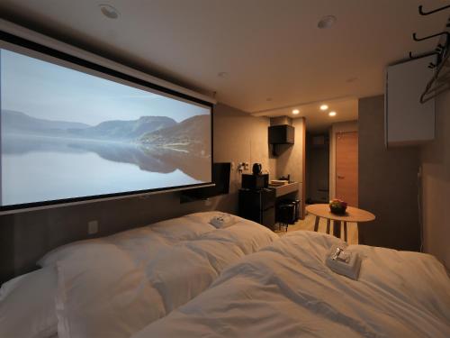 a large projection screen in a hotel room with a bed at Oizumigakuen House in Yagisawa