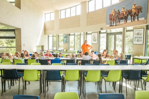 uma imagem de uma sala de aula com crianças sentadas em torno de uma mesa grande em Jeugdherberg De Peerdevisser em Oostduinkerke