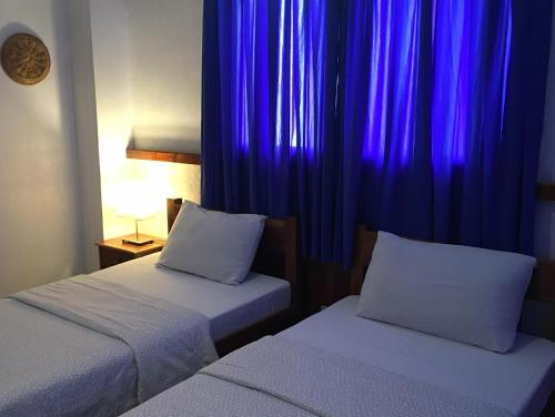 邦劳帕西路拿旅馆的紫色窗帘间内的两张床