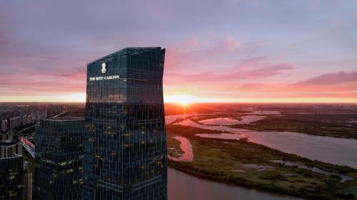um edifício alto com o pôr-do-sol ao fundo em The Ritz-Carlton, Harbin em Harbin