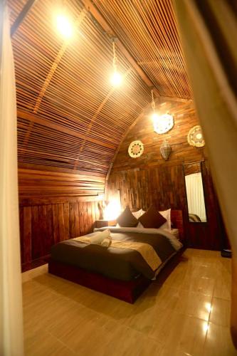 a bedroom with a bed in a room with wooden walls at Bukit Delapan Glamping & Coffee in Kubupenlokan