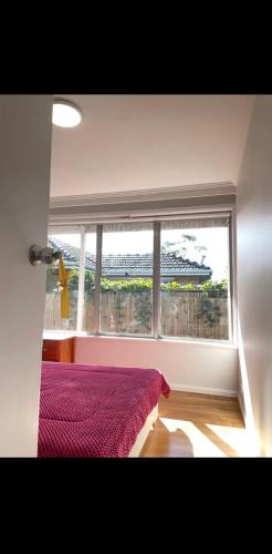 a bedroom with a large window and a red bed at Budget-friendly room near Sunshine Station to CBD in Sunshine