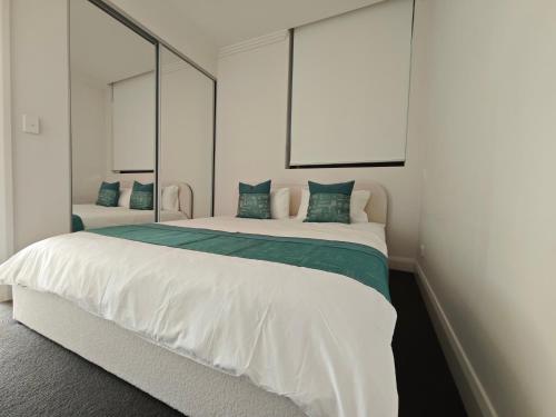 a bedroom with a large white bed with mirrors at SkyView Stay - Sydney Olympic Park in Sydney
