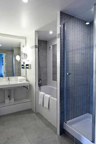 a bathroom with a shower and a tub and a sink at Hôtel du Golf in Lumbres