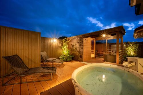 a jacuzzi tub on a deck at night at Tendo Onsen TAKINOYU in Tendo