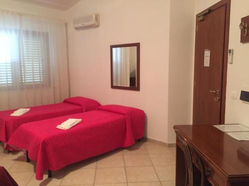 a hotel room with two beds and a mirror at Castelvetere Hotel in Caulonia