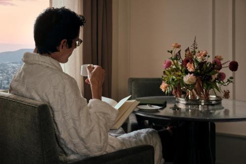 a woman sitting at a table with a book and a cup of coffee at The Huntington Hotel in San Francisco