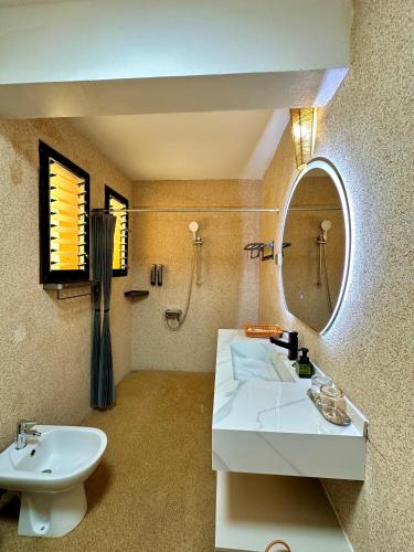 a bathroom with a sink and a mirror at Holiday Beach Hotel in Nosy Be