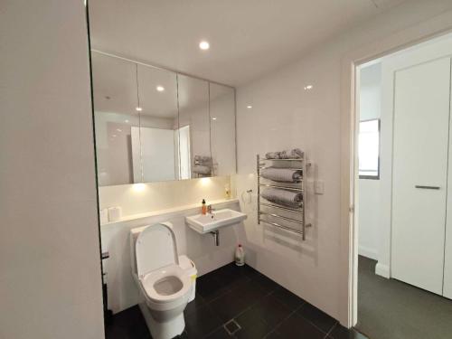 a white bathroom with a toilet and a sink at SkyView Stay - Sydney Olympic Park in Sydney