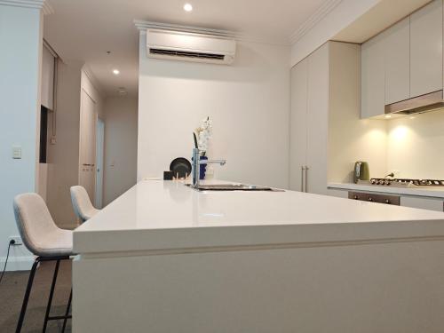 a white kitchen with a sink and a counter at SkyView Stay - Sydney Olympic Park in Sydney