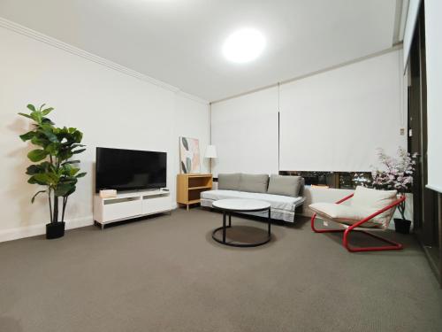 a living room with a couch and a tv at SkyView Stay - Sydney Olympic Park in Sydney
