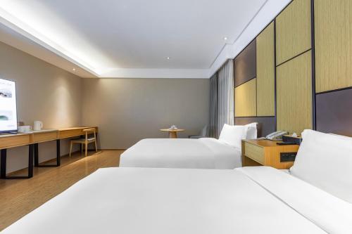 a hotel room with two beds and a desk at JI Hotel Shanghai Changshou Road in Shanghai