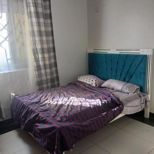 a bed with a blue headboard in a bedroom at Mikes apartment in Mombasa