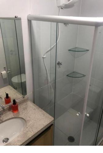 a bathroom with a glass shower and a sink at Apartamento JTR Maceio AL in Maceió