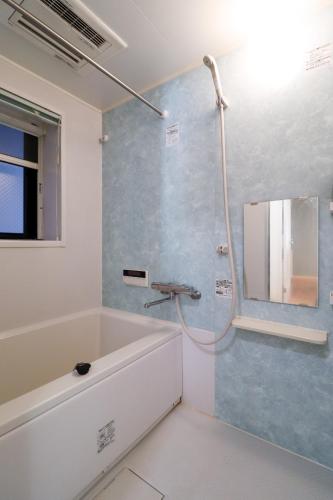 a bathroom with a bath tub and a mirror at Al Di La 四谷 in Tokyo
