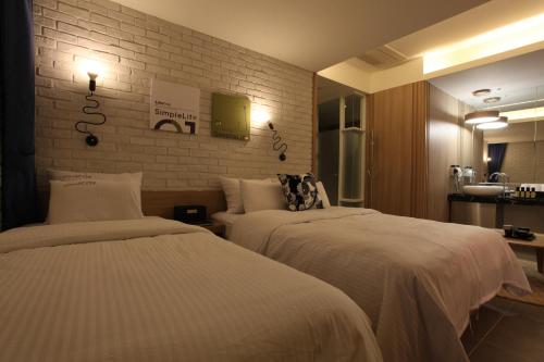 a hotel room with two beds and a brick wall at Kobos Hotel in Seoul