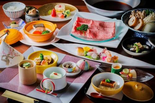 a table with plates of food and bowls of food at Takinoyu Hotel in Tendo