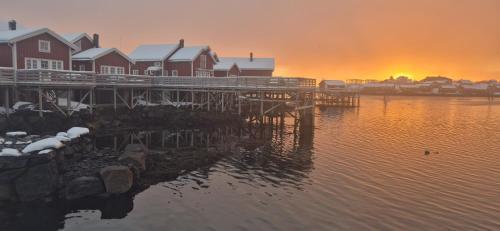 a dock with houses on the water at sunset at Andøy Vest Rorbuer Reine in Reine